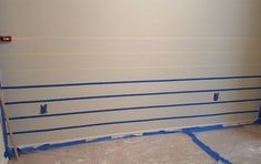 an unfinished room with blue tape on the wall and white paint covering the walls in preparation for painting