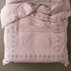 an unmade bed with pink comforter and pillowcases on top of it