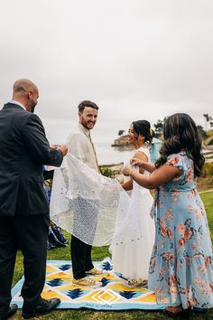 a group of people standing on top of a grass covered field next to each other