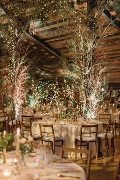 the tables are set with white tablecloths and centerpieces, surrounded by lighted trees