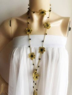 a mannequin wearing a white dress with yellow flowers on the neck and black beads