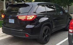 the rear end of a black suv parked in a parking lot next to another car