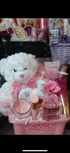 a white teddy bear sitting on top of a pink basket filled with cosmetics and other items