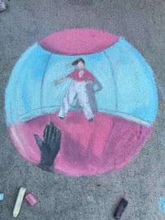 a chalk drawing of a girl in a ball on the ground with other chalk crayons