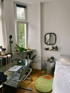 a bedroom with a bed, desk and bookshelf next to a large window