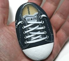 a hand holding a black and white painted shoe