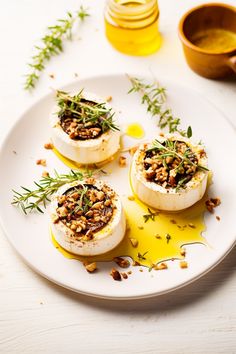 three deviled eggs on a white plate topped with nuts and herbs next to honey