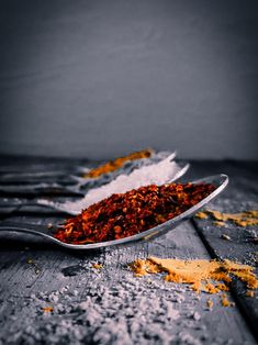 a spoon full of spices sitting on top of a wooden table