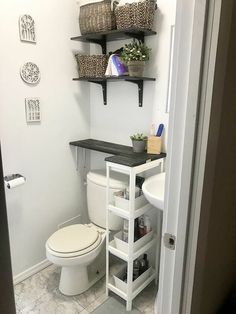 a white toilet sitting in a bathroom next to a shelf filled with bottles and baskets