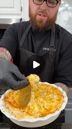 a man in an apron is holding a plate with food on it and wearing gloves