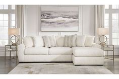 a large white sectional couch in a living room with two lamps on the side tables