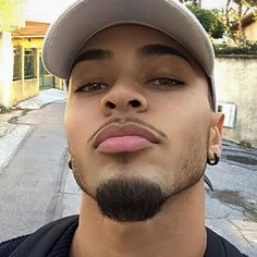 a man wearing a baseball cap and piercings on his ears is looking at the camera