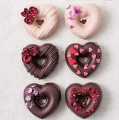 six donuts with chocolate frosting and sprinkles in the shape of hearts