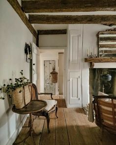 a chair and table in a room with wood floors, white walls and beams on the ceiling