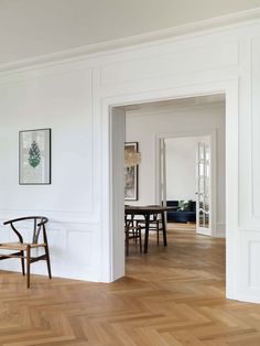 a room with white walls and wood flooring in the center is an empty dining table