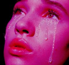 a woman's face is covered with water drops from her eyeliners as she stares into the distance