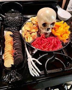 a skull sitting on top of a stove next to a plate filled with different types of food