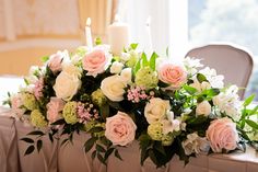 a bouquet of flowers sitting on top of a table next to a lit candle and window