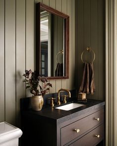 a bathroom sink sitting under a mirror next to a white toilet and wooden counter top