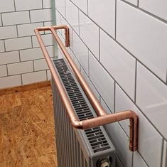 a radiator in the corner of a bathroom with white tiles and wood flooring