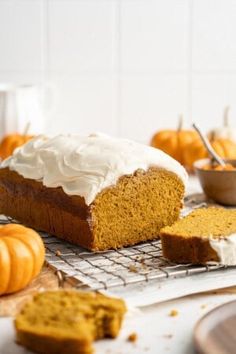 a loaf of pumpkin bread sitting on top of a cooling rack next to two slices of cake