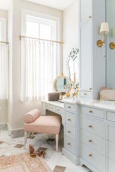 a pink chair sitting in front of a bathroom mirror next to a sink and vanity