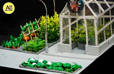 a miniature garden is shown with green plants and flowers in the foreground, along with an artificial greenhouse