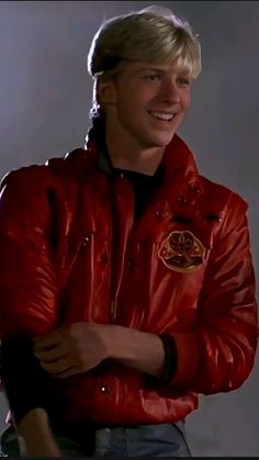 a young man in a red leather jacket smiling