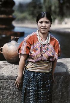 an old photo of a woman standing next to a vase