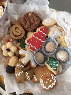 a basket filled with lots of different types of cookies and pastries on top of paper