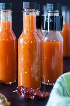 three bottles filled with different types of sauces on a table next to other items