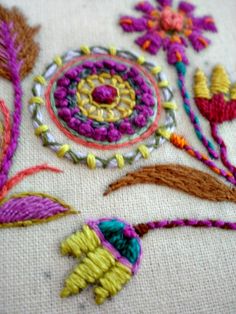 a close up of some embroidery on a piece of cloth with flowers in the middle