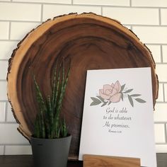 a wooden sign sitting on top of a table next to a potted plant