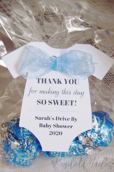 a blue and white baby shower gift in a plastic bag with the words thank you for making this day so sweet