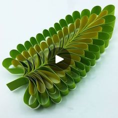 a video demonstrating how to make an origami leaf sculpture with green and yellow colors