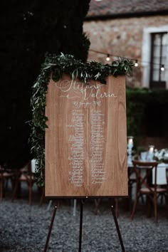 a wooden sign sitting on top of a table covered in flowers and greenery next to tables