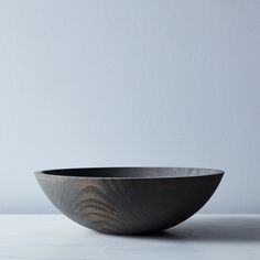 a large black bowl sitting on top of a table next to a white wall and floor