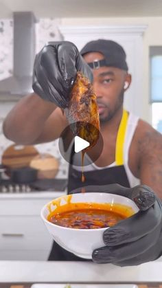 a man in black gloves is holding a bowl of soup