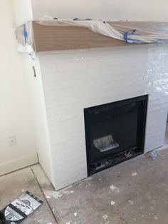 the fireplace is being painted white with blue tape on it's mantle and there are other items scattered around