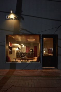 the reflection of a dining room table and chairs in a store front window at night