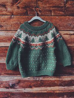 a green sweater hanging on a wooden wall