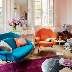 a living room filled with furniture and flowers in vases on top of windowsill