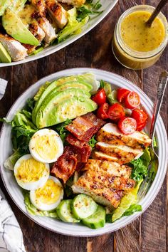 two plates filled with salad and dressing on top of a wooden table