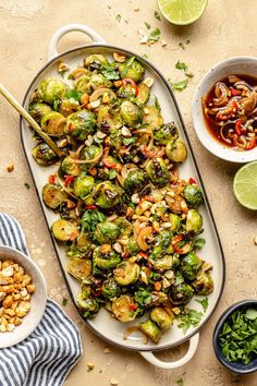 a platter filled with brussel sprouts, peanuts and other vegetables