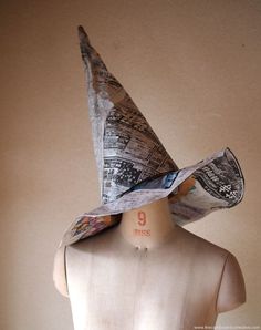 a mannequin wearing a paper hat with newspaper pages on it