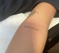 a woman's arm with the word free mind tattooed on her left arm, in black ink