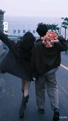 a man and woman walking down the street with their arms around each other while carrying food