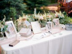 a table topped with pictures and flowers on top of a white cloth covered tablecloth