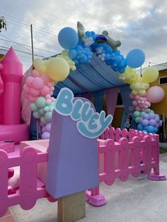 a bunch of balloons that are in front of a pink and blue structure with the word bly on it