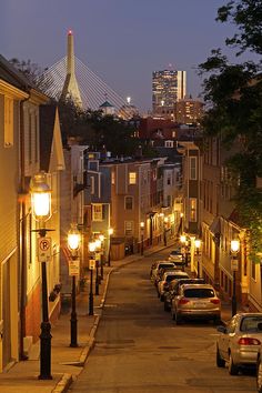 a city street at night with cars parked on both sides